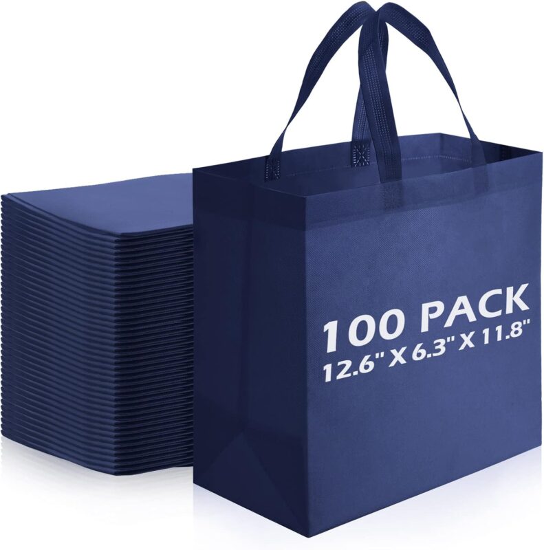 A stack of 100 navy blue reusable non-woven tote bags with handles, neatly folded and ready for use.