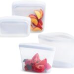 Four clear Stasher reusable silicone bags, including snack, sandwich, 2-cup, and 4-cup sizes, neatly arranged.