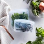 Four clear Stasher reusable silicone bags, including snack, sandwich, 2-cup, and 4-cup sizes, neatly arranged.